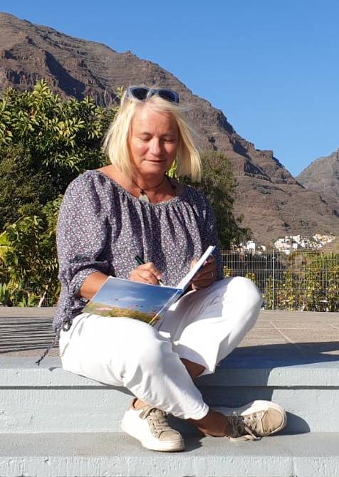 Iris sitzt mit einem Buch in der Sonne auf La Gomera